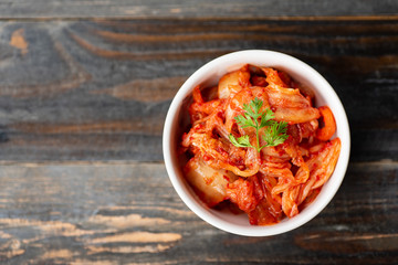Kimchi cabbage in a bowl on wooden background, top view, Korean food - obrazy, fototapety, plakaty