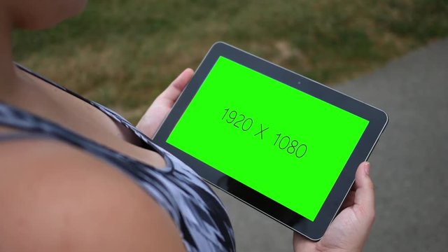 Tablet with green screen close up during the day near walking trail