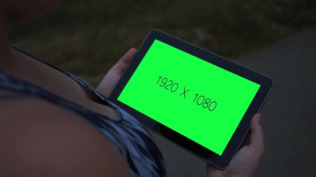 Tablet with green screen close up at night near walking trail