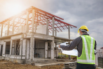 Professional engineer architect worker with protective helmet and blueprints paper at house building construction site