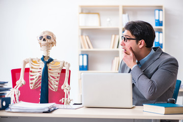 Businessman working with skeleton in office