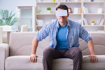 Man with virtual reality glasses playing at home