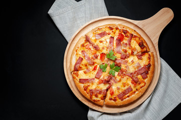Delicious Italian pizza sliced ham, bacon and cheese with food ingredients on old kitchen table.