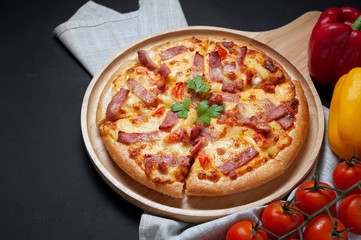 Delicious Italian pizza sliced ham, bacon and cheese with food ingredients on old kitchen table.