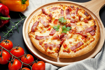 Delicious Italian pizza sliced ham, bacon and cheese with food ingredients on old kitchen table.