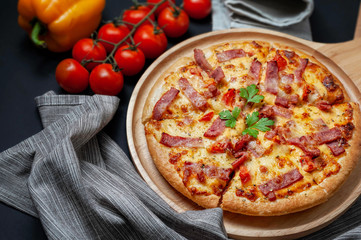 Delicious Italian pizza sliced ham, bacon and cheese with food ingredients on old kitchen table.