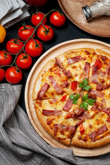 Delicious Italian pizza sliced ham, bacon and cheese with food ingredients on old kitchen table.