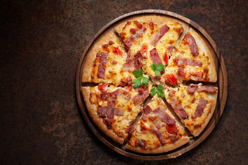 Delicious Italian pizza sliced ham, bacon and cheese with food ingredients on old kitchen table.