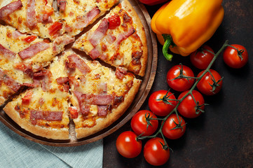 Delicious Italian pizza sliced ham, bacon and cheese with food ingredients on old kitchen table.