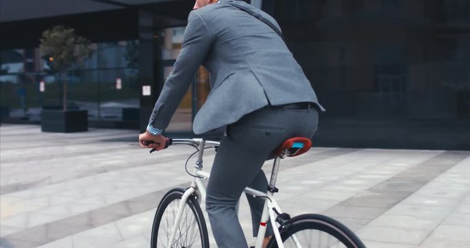 TRACKING Handsome young adult man wearing suit riding his classic bicycle to work in the morning. 4K UHD 60 FPS SLOW MOTION