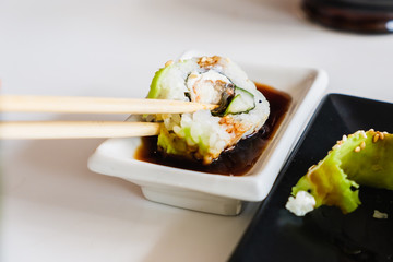 Sushi roll with eel and avocado, chopsticks. Traditional Japanese meal.