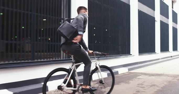 TRACKING Handsome young adult man wearing suit riding his classic bicycle to work in the morning. 4K UHD