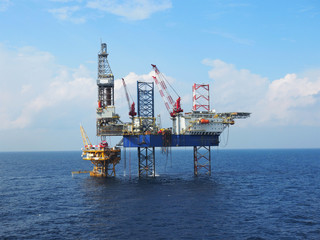 Jack up rig is set up for drilling operations over offshore static platform with blue sea and skies...
