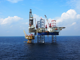 Jack up rig is set up for drilling operations over offshore static platform with blue sea and skies...