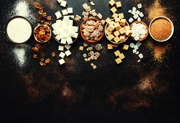 Obraz na płótnie Canvas Set of different white and brown sugar in assortment, dark background, top view