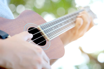 Woman's hand Play Guitar ukulele  Natural bokeh background