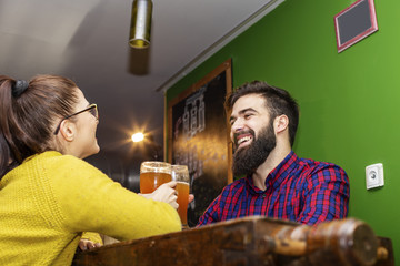 Young couple looking each other in local pub with glass of beer