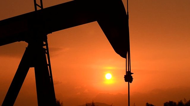 pumpjack at an oil drilling site and sunset