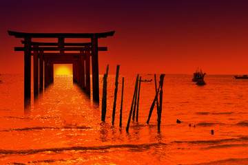 Fototapeta premium silhouette torii wooden Japanese pillar stand on over the sea and sunset sky