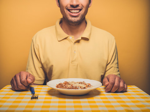 Young man against yellow eating mince