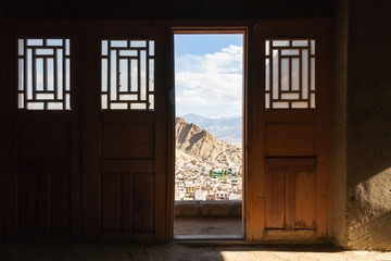 Looking through the wooden ancient door to old town of Leh city from Leh palace in Leh Ladakh, Jammu and Kashmir, India with warm sunlight. (depth of field)