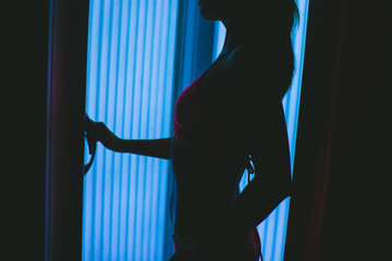 Beautiful slim blonde girl tans in the solarium