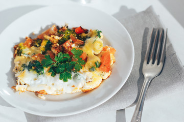 Scrambled eggs with tomatoes and greens on an white background