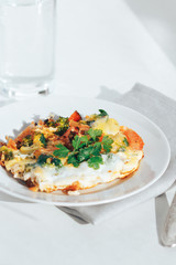 Scrambled eggs with tomatoes and greens on an white background