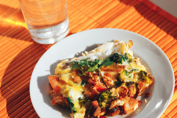 Scrambled eggs with tomatoes and greens on an orange background