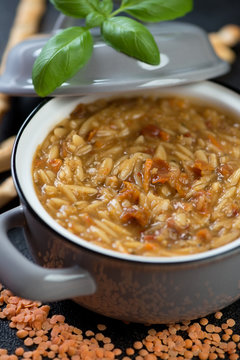 Close-up of italian soup with red lentils and pasta in a pot, selective focus