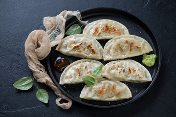 Metal tray with fried korean potstickers, horizontal shot over black stone background