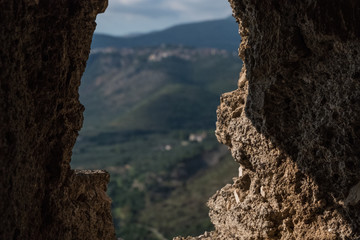 Wallpaper background of landscape view from a hole on an antique stone wall in a medieval town. Sermoneta. Italy. No people.