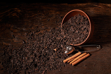 Top view of dried black tea in clay bowl on wooden table. Concept of tea production. Macro, close up