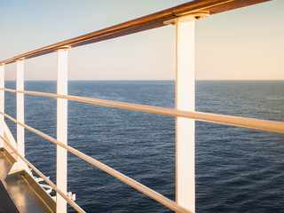 Railing on the empty, open deck of a cruise liner against the background of sea waves. Sunset photo