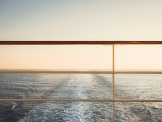 Railing on the empty, open deck of a cruise liner against the background of sea waves. Sunset photo