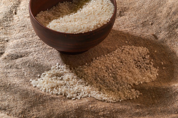 Raw rice in bowl on sackcloth. Uncooked food. selective focus