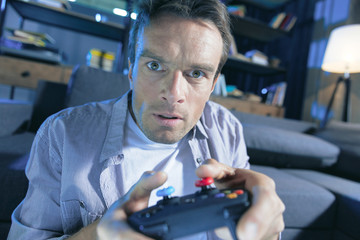 Way to relax. Nice handsome pleasant man looking at the screen and expressing his emotions while...