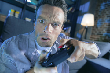 Modern games. Nice handsome emotional man using a game console and playing a video game while...