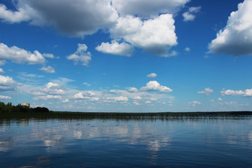 Lake Vysokinskoye in the summer, with the reflection of white clouds in the water. Leningrad Region, Russia.