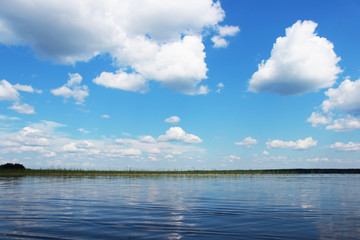 Lake Vysokinskoye in the summer, with the reflection of white clouds in the water. Leningrad Region, Russia.