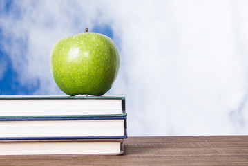 concept of back to school with apple and books stacked on background