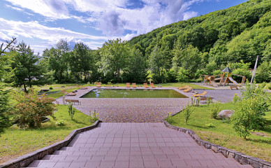 A small uncleaned pool with sun loungers around it. There are no vacationers nearby