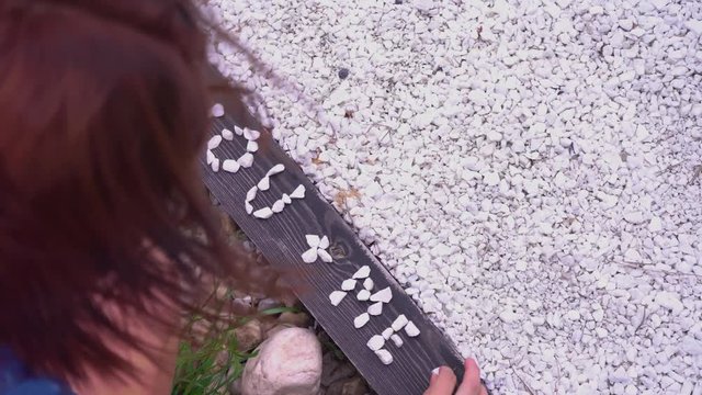 Inscription about love. The girl puts out of white pebbles the inscription you and me are equal love