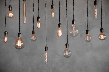 Edison retro lamp Incandescent bulbs on gray plaster wall background in loft. Concept Vintage style