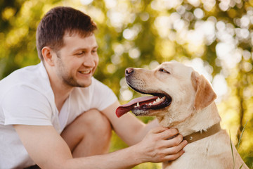Owner man caressing smile gently labrador dog outdoors in sunset. Concept friendship