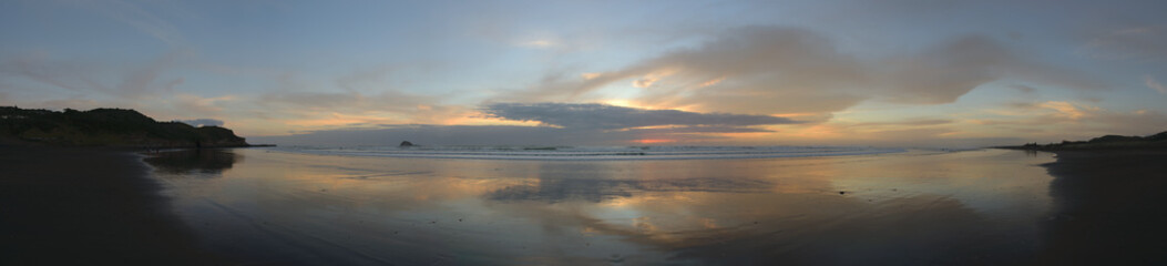 Spiegelung im Wasser am Sandstrand in Muriwai Beach