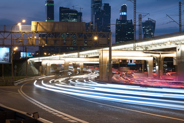 Fototapeta na wymiar the light trails on road with junction and the modern building background