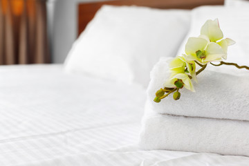 towels and flower on bed in hotel room