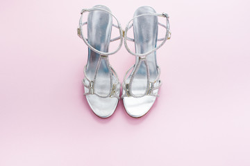 Fashionable women's sandals silver color on a pink background.