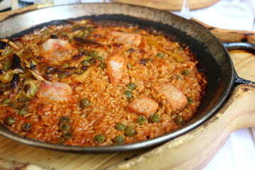 Paella with tuna, peas and onion, cooked and served in a traditional pot. Paella is a traditional Spanish rice dish. Selective focus. 